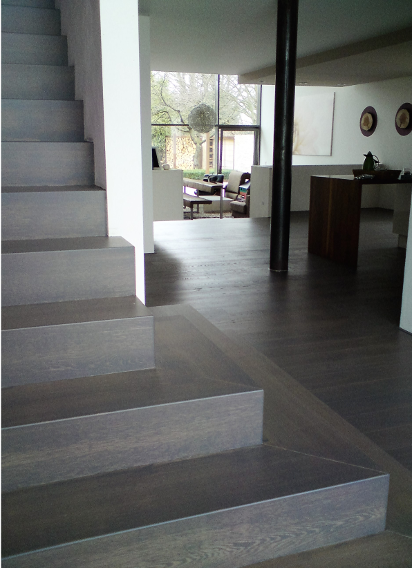 Eine Treppe in einem Haus mit Blick auf das Wohnzimmer. Helle Farben und gemütliche Einrichtung.