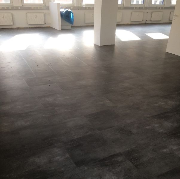 Dunkelgrauer Vinylboden mit Lichteinfall.