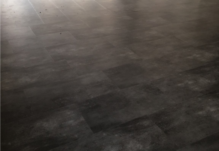 Dunkelgrauer Vinylboden mit Lichteinfall.